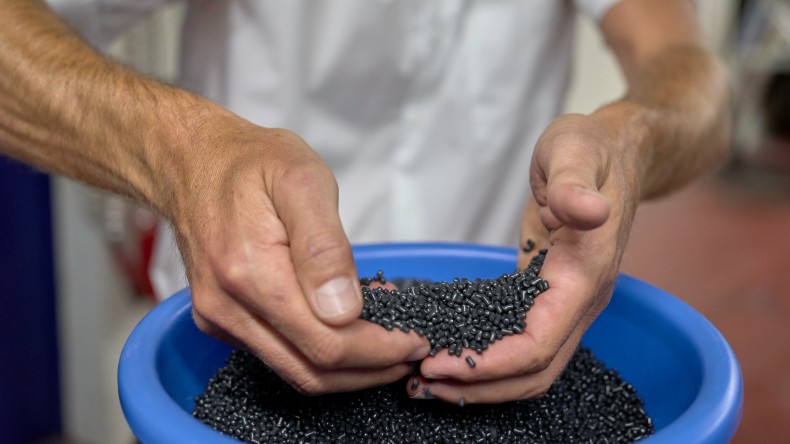 Person holding black plastic pellets (© Ben Huggler)