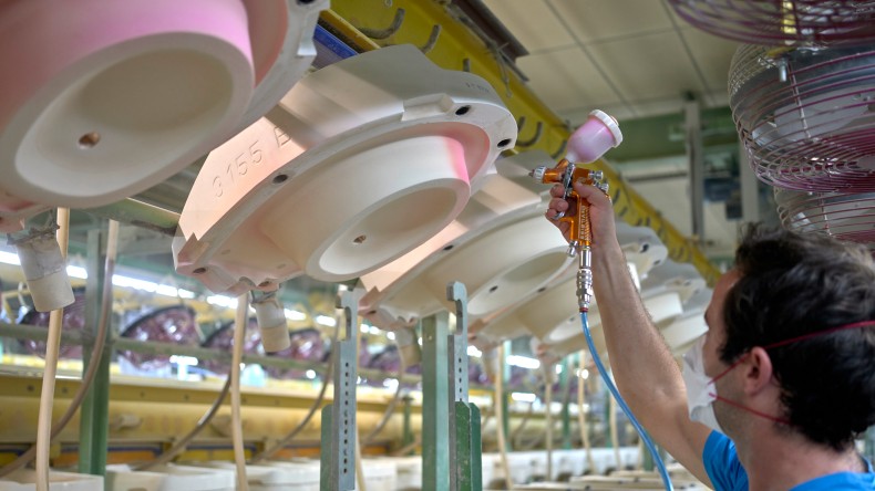 Employee sprays talc powder mixed with water onto the ceramic mould.