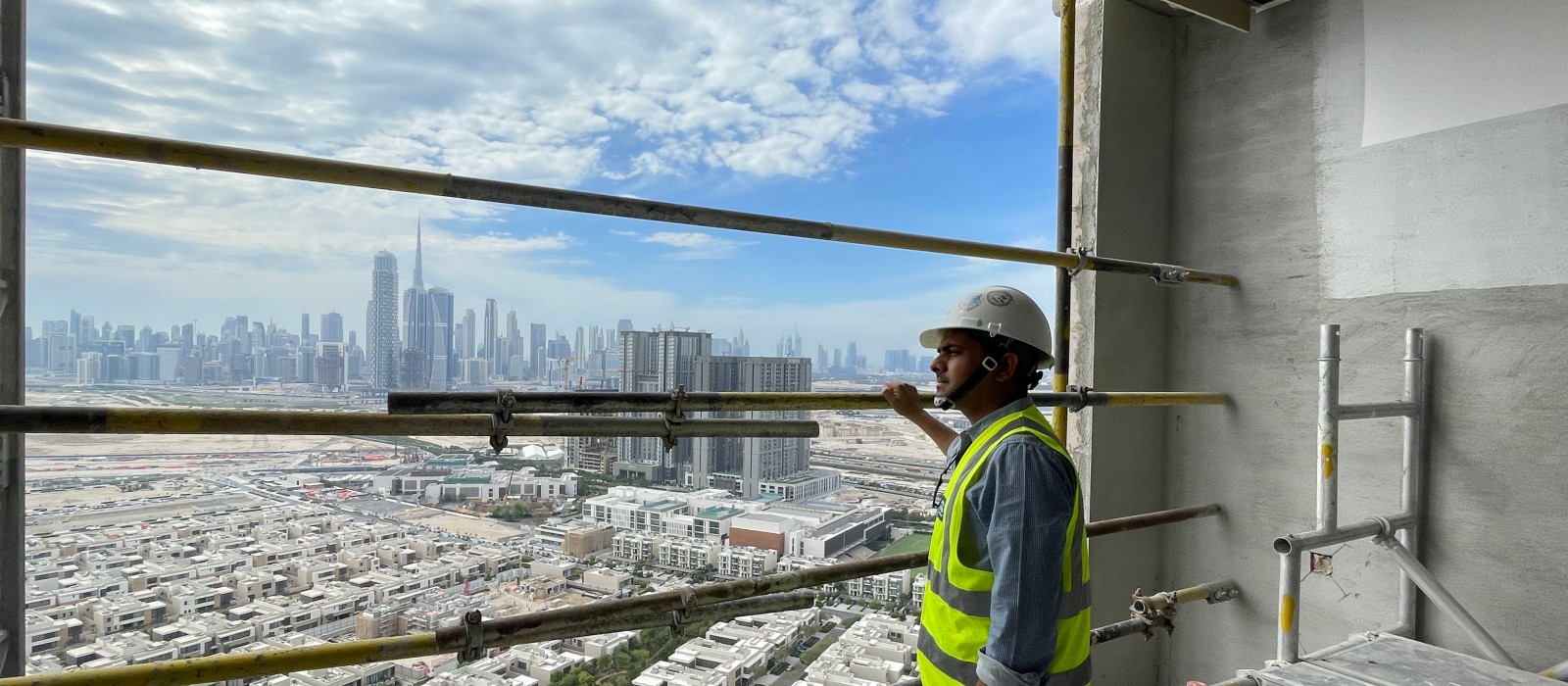 Above the rooftops of Dubai: Vineet Kumar Bhaskar on a construction site. The Dubai skyline in the background.