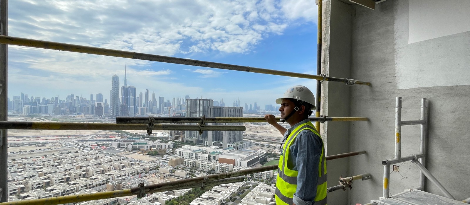 Above the rooftops of Dubai: Vineet Kumar Bhaskar on a construction site. The Dubai skyline in the background. Above the rooftops of Dubai: Vineet Kumar Bhaskar on a construction site. The Dubai skyline in the background.