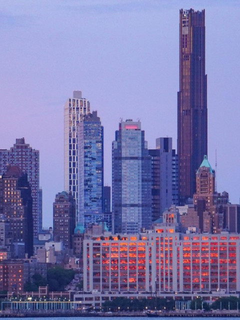 City skyline featuring a mix of modern skyscrapers during a sunset with pastel skies.