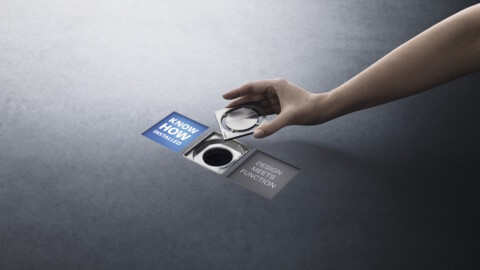 Eine Hand platziert eine Ablaufabdeckung über einem quadratischen Bodenablauf zwischen den zwei Claims "Know How Installed" und "Design Meets Function".