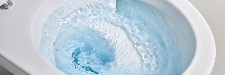 Toilet mit wirbelndem blauen Spülwasser, von oben in Nahaufnahme.