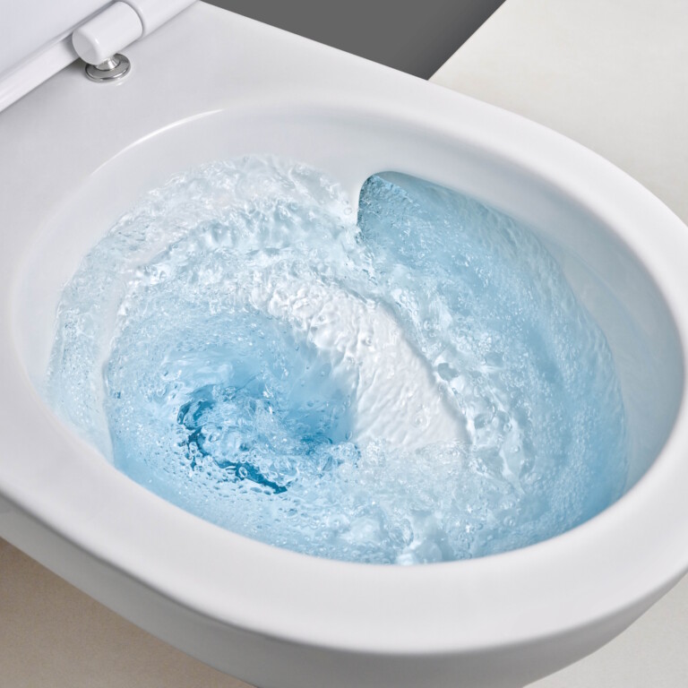 Toilet mit wirbelndem blauen Spülwasser, von oben in Nahaufnahme.