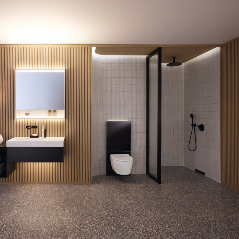 Geräumiges, modernes Badezimmer mit hölzernen Lamellenwänden, beleuchtetem Spiegel, Waschbecken, Monolith und offener Dusche.