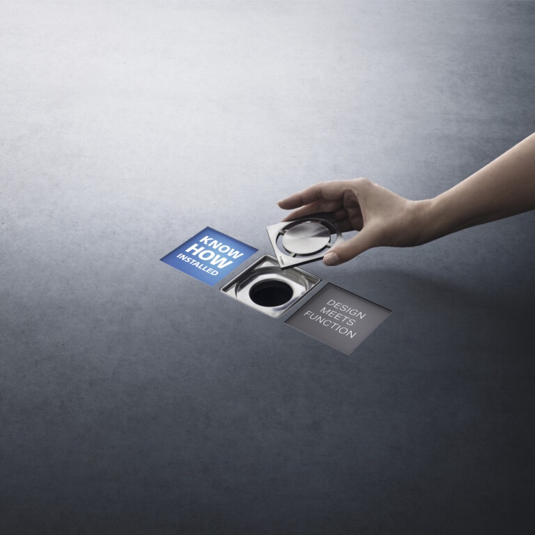 A hand places a drain cover over a square floor drain between the two claims ‘Know-how Installed’ and ‘Design Meets Function’.