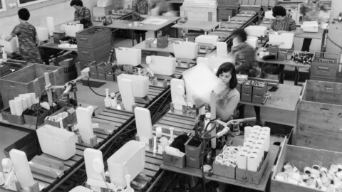 Industrial hall with conveyor belts where employees in a factory process cisterns.