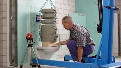 Mann analysiert Toilette, auf der Gewichte sind, um die Stabilität und Belastbarkeit zu prüfen.