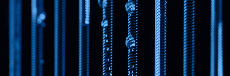 Vertical springs with varying widths and small droplets, illuminated in blue against a dark background.