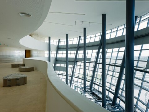 Moderne Architektur mit geschwungenen Linien und grossen Fenstern, die viel Tageslicht hereinlassen.