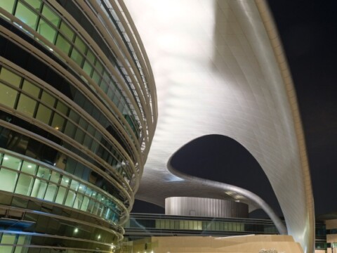 Moderne Architektur mit gewölbten Formen und glänzenden Oberflächen, beleuchtet bei Nacht.