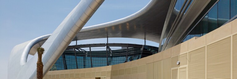 Moderne Architektur mit geschwungenen Linien und Glasfassade, Besucher gehen ins Gebäude.