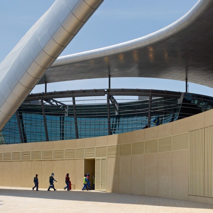 Moderne Architektur mit geschwungenen Linien und Glasfassade, Besucher gehen ins Gebäude.