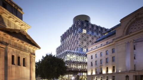 Moderne Glasarchitektur zwischen historischen Gebäuden bei Dämmerung.