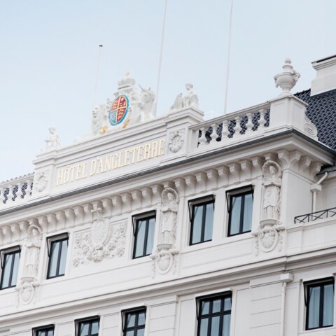 A close-up view of a classical-style building facade featuring ornate architectural details, multiple windows, and a decorative crest at the top.