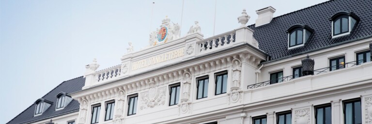 A close-up view of a classical-style building facade featuring ornate architectural details, multiple windows, and a decorative crest at the top.