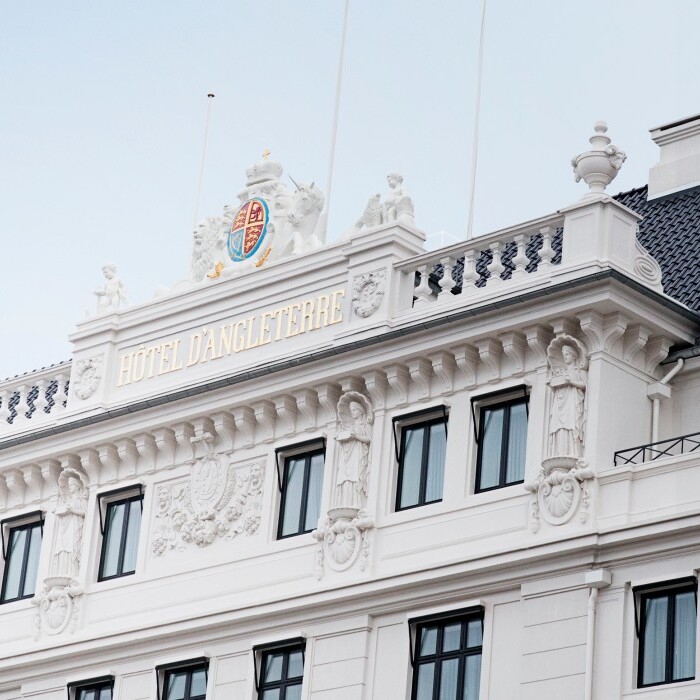 A close-up view of a classical-style building facade featuring ornate architectural details, multiple windows, and a decorative crest at the top.