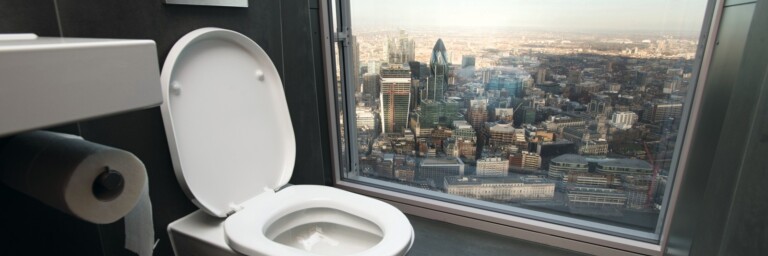 A modern bathroom featuring a toilet with an open lid,  and a large window showcasing a cityscape view.