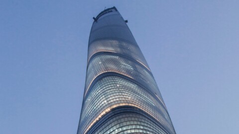 Der Shanghai Tower mit seiner charakteristischen spiralförmigen Fassade vor einem blauen Himmel.