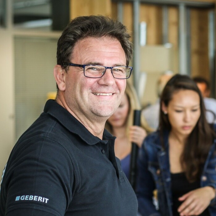 Eine Gruppe von Menschen in einem Raum, die miteinander interagieren, während ein Mann in der Mitte lächelt.