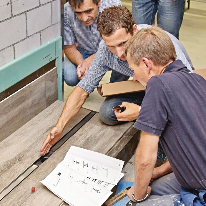Several individuals gathered around a workbench, collaborating on a project.