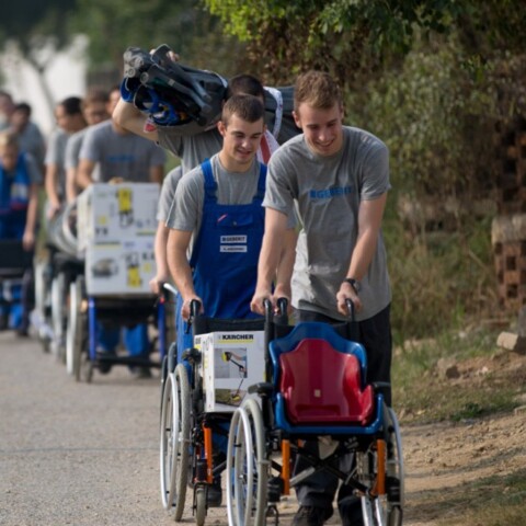 A group of people walking along a path while pushing wheelchairs.