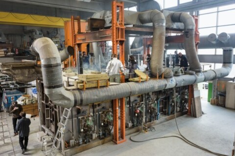 An industrial manufacturing facility featuring large machinery and workers near a complex assembly system.