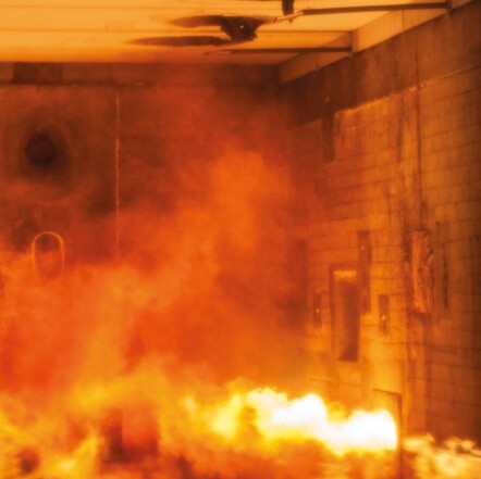 A room engulfed in flames and thick smoke, with a hazy, orange glow.