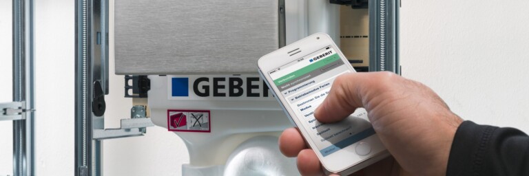 Eine Hand, die ein Smartphone hält mit einer App, um den Spülkasten zu kontrollieren.