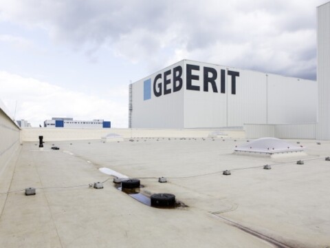 A flat roof with a Pluvia roof drainage system and the word “GEBERIT” written on the building.