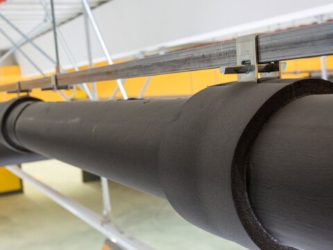 A close-up of a large, dark cylindrical pipe resting on a supportive framework.