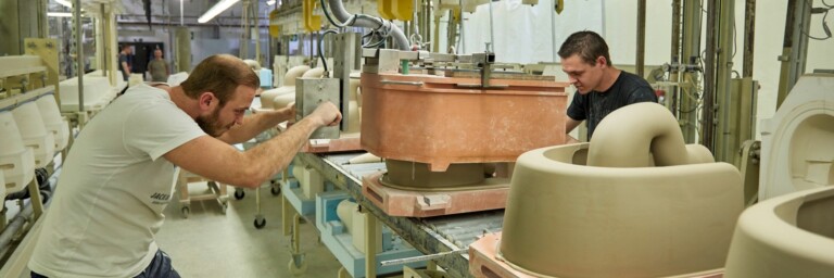Two workers in a factory that manufacture toilet ceramics.