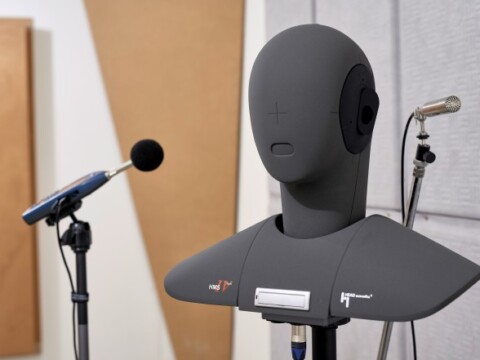 Ein künstlicher Kopf mit Mikrofonen in einem akustisch behandelten Raum, umgeben von schalldämpfenden Paneelen.