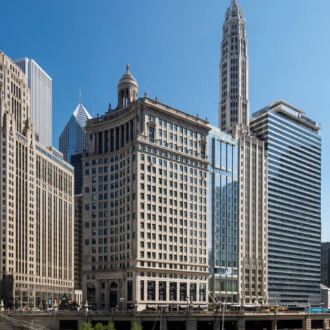 A panoramic view of a modern city skyline featuring a mix of tall skyscrapers and historic buildings under a clear blue sky.