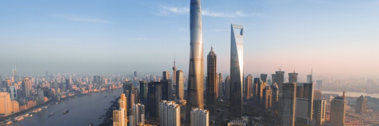 A panoramic view of Shanghai's skyline featuring tall modern skyscrapers like the Shanghai Tower and the Jin Mao Tower alongside the Huangpu River.