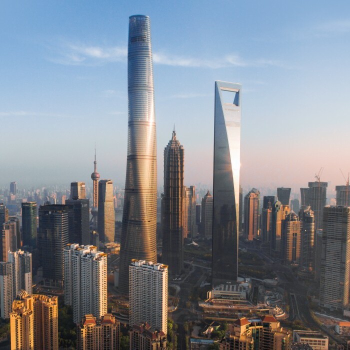 A panoramic view of Shanghai's skyline featuring tall modern skyscrapers like the Shanghai Tower and the Jin Mao Tower alongside the Huangpu River.