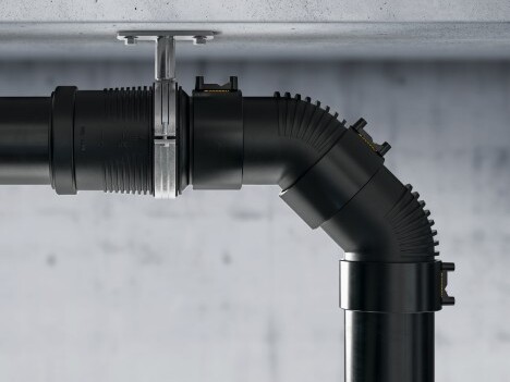 Schwarze Rohrverbindung mit einem knickbaren Abschnitt, montiert an einer Decke.