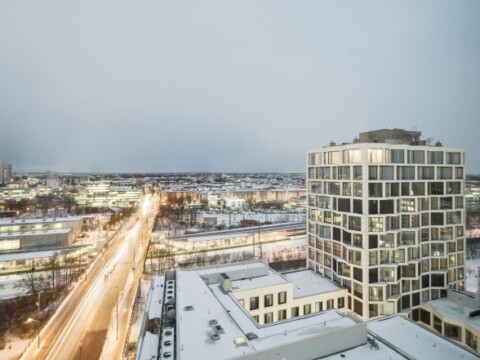 Stadtansicht mit modernen Gebäuden und einer schneebedeckten Strasse, unter grauem Himmel.