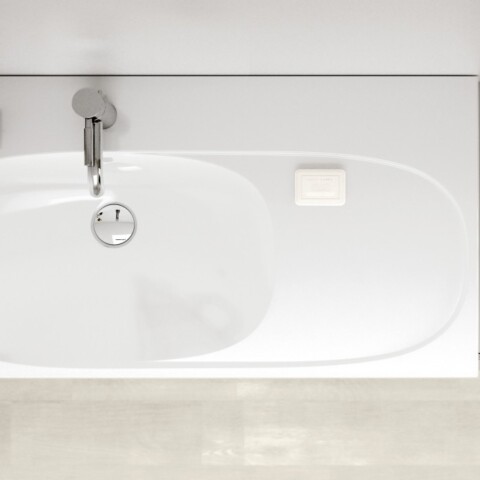 Eine modernes, weisses Waschbecken mit einer silbernen Armatur, daneben ein kleiner Topf mit einer Pflanze und zwei Zeitschriften auf einem grauen Ablagetisch.