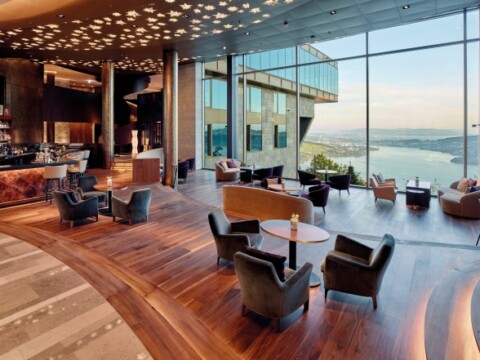 Elegantes moderne Lounge mit Holzfussboden, grossen Fenstern und Blick auf das Wasser.