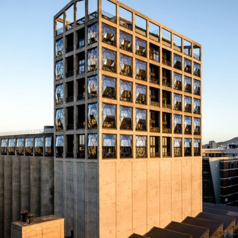 Moderne Architektur eines Hochhauses mit einer markanten Fassade und Blick auf Stadt und Berge.