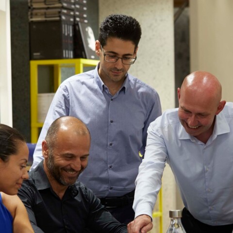 A group of six people gathered around a table, engaging in discussion.