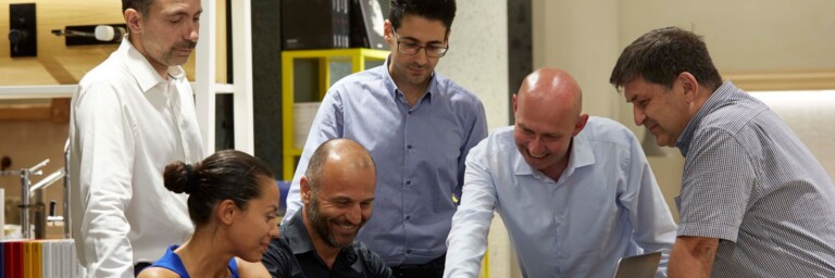 A group of six people gathered around a table, engaging in discussion.