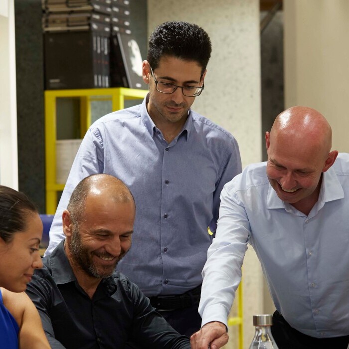 A group of six people gathered around a table, engaging in discussion.