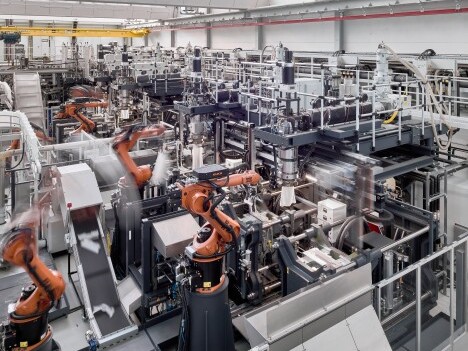 A large industrial assembly line filled with numerous robotic arms and machines, working simultaneously in a factory setting.