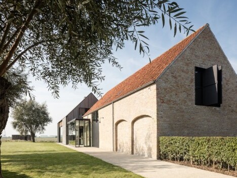 Modernes Gebäude mit rotem Satteldach, grossen Fenstern und grüner Umgebung.