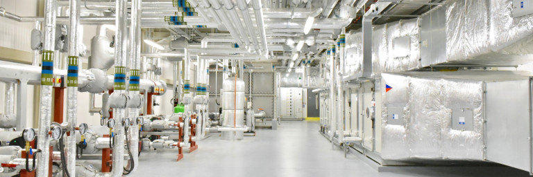 Industrielle Umgebung mit Rohrleitungen, Lüftungsanlagen und glattem, hellem Boden.