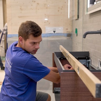 Ein Handwerker in blauer Kleidung installiert ein Waschbecken.