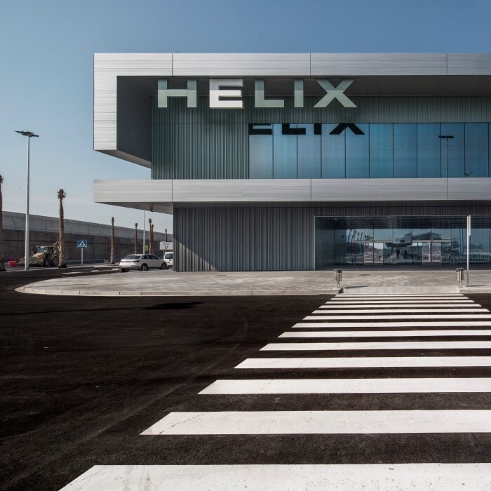 Modern building with large glass windows and "HELIX" signage, viewed from a crosswalk.