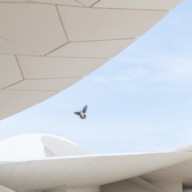 Ein moderner, architektonischer Komplex mit geschwungenen, weissen Strukturen und einem Vogel, der darüber fliegt.